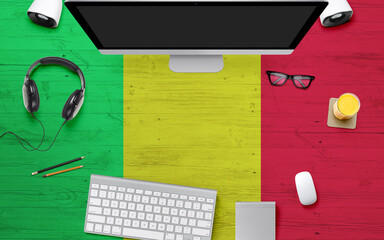 Mali flag background with headphone,computer keyboard and mouse on national office desk table.Top view with copy space.Flat Lay.