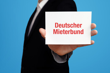 Deutscher Mieterbund (DMB). Geschäftsmann im Anzug hält Karte in die Kamera. Der Begriff Deutscher Mieterbund steht im Schild. Symbol für Business, Finanzen, Statistik, Analyse, Wirtschaft