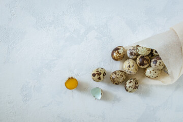 Obraz na płótnie Canvas A packet of craft paper with quail eggs on a light background with the texture of plaster. Healthy eating, healthy food concept. Horizontal orientation, selective focus, copy space