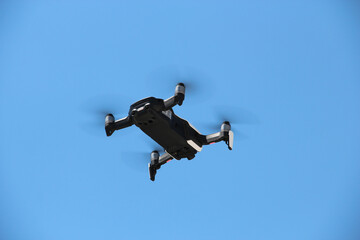 Flying drone with blue sky background controlled by professional photographer