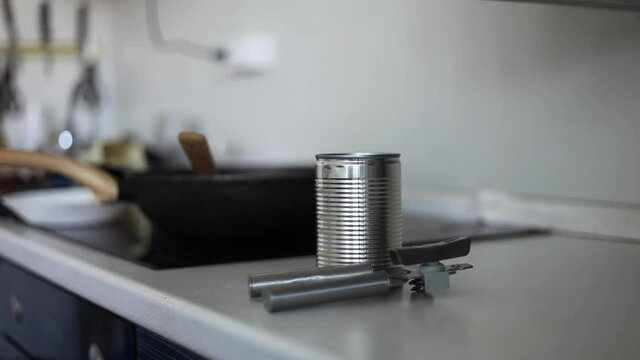 A woman in the kitchen opens a can. Hand open canned food in metal can. Close up canned goods non perishable food storage goods in kitchen home