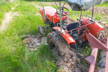 Wheel of old tractor plowing the soil for planting stuck the mud in agricultural fields.