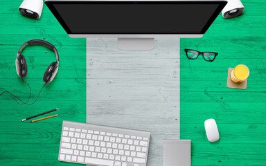 Nigeria flag background with headphone,computer keyboard and mouse on national office desk table.Top view with copy space.Flat Lay.