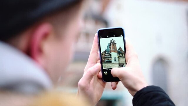 White male taking a photograph with a smartphone of a church