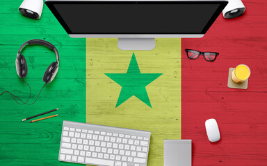 Senegal flag background with headphone,computer keyboard and mouse on national office desk table.Top view with copy space.Flat Lay.