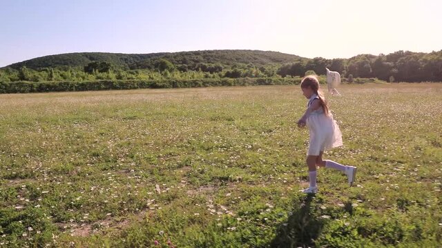 adorable child girl running in the meadow. Cute little girl enjoy and having fun at grass field in springtime. Happy family in summer concept. a little beautiful girl in a dress runs a large field. ch