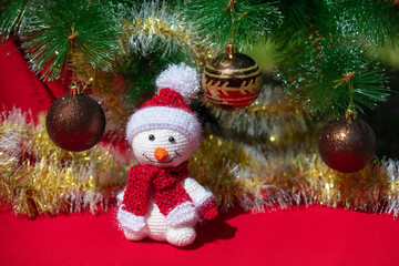 New year greeting card. Toy snowman on a red background with a decorated Christmas tree. Space for text