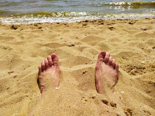 Feet in the sand on the beach by the sea