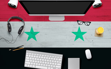 Syria flag background with headphone,computer keyboard and mouse on national office desk table.Top view with copy space.Flat Lay.