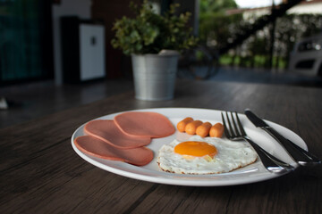 English breakfast, fried eggs, ham and filling on a wooden table