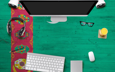Turkmenistan flag background with headphone,computer keyboard and mouse on national office desk table.Top view with copy space.Flat Lay.