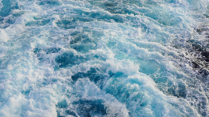 seething water. texture of blue foamy sea water. clear ocean water background. sun reflection