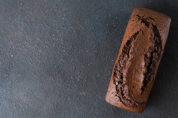 Freshly baked homemade chocolate bread or cake on dark background, rustic style.