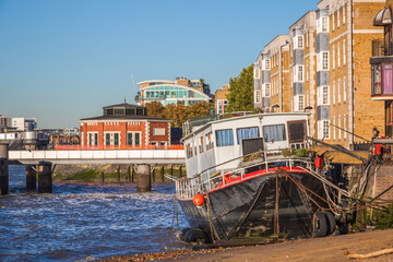 Fototapeta na wymiar A stranded boat on River Thames with Rotherhithe Tunnel ventilation shaft in the background