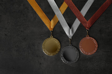 Gold, silver and bronze medals on grey stone background, flat lay. Space for design