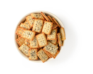 Small salty rectangular crackers with poppy and sesame seeds in a beige ceramic bowl isolated on a white background. Crispy wheat flour snack and beer appetizer.