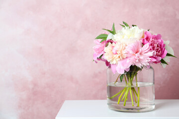 Bouquet of beautiful peonies in vase on white table. Space for text