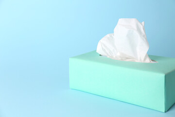 Box of paper tissues on light blue background. Space for text
