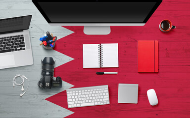 Bahrain flag background with headphone,camera, notebook and mouse on national office desk table.Top view with copy space.Flat Lay.