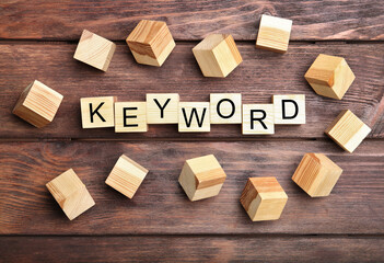 Cubes with word KEYWORD on wooden background, flat lay