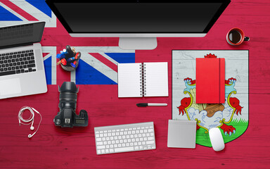 Bermuda flag background with headphone,camera, notebook and mouse on national office desk table.Top view with copy space.Flat Lay.
