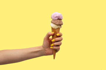 Woman's hand holding an ice cream in a yellow background