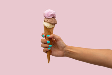 Woman's hand holding an ice cream over a pink background