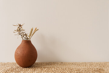 Dry rye, wheat stalks in red clay pot on white background. Minimal interior design decoration.