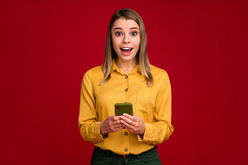 Fototapeta premium Portrait of her she nice attractive lovely charming amazed cheerful cheery girl using cell sale app fasts peed connection isolated over bright vivid shine vibrant red color background