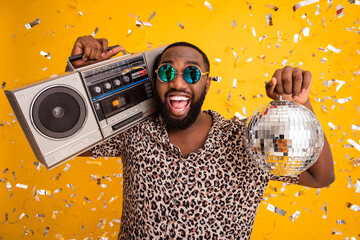 Close-up portrait of his he nice handsome bearded cheerful cheery cool emotional guy holding in hands shine disco ball carrying player isolated on bright vivid shine vibrant yellow color background - obrazy, fototapety, plakaty