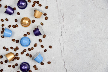 Close up colorful capsules or pods for coffee mashine with some roasted grains on concrete background. 