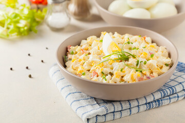 A light egg salad with celery, gherkin, pepper and mayonnaise. Served in a bowl on a light background. Front view.