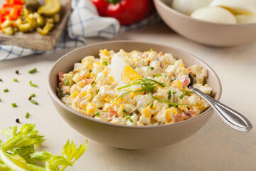 A light egg salad with celery, gherkin, pepper and mayonnaise. Served in a bowl on a light background. Front view.