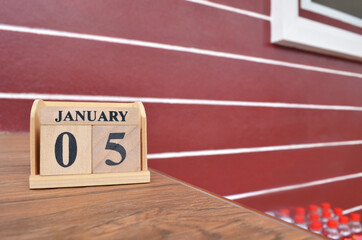 January 5, Number cube with wooden table beside the wall.