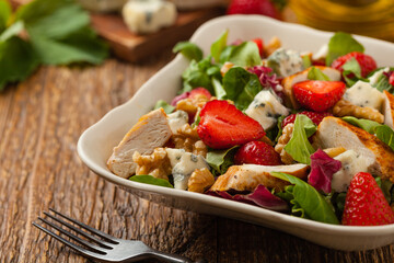 Delicious salad with fried chicken, blue cheese, strawberries and walnuts. Front view.