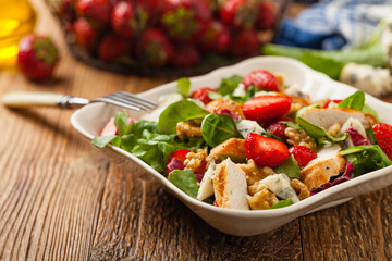 Delicious salad with fried chicken, blue cheese, strawberries and walnuts. Front view.