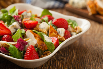 Delicious salad with fried chicken, blue cheese, strawberries and walnuts. Front view.
