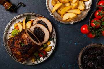 Whole roasted pork loin stuffed with dried plum. Top view. Dark blue background.
