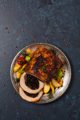 Whole roasted pork loin stuffed with dried plum. Top view. Dark blue background.