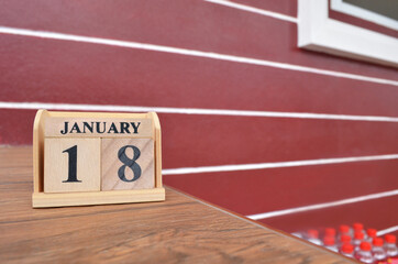 January 18, Number cube with wooden table beside the wall.