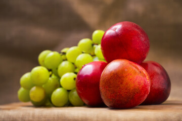 Fresh juicy white grapes and nectarines on a wooden board, Hessian backdrop, Still life. Selective focus.