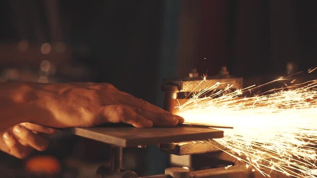 Man sharpening knife with sparks. Work on a sharpening machine.