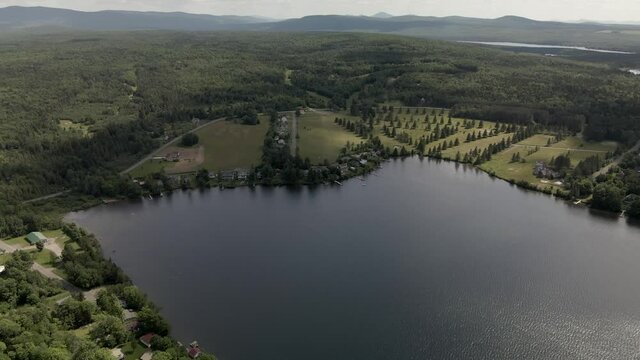 Lush Green Meadow And Mountain Hills Of Mount Pinacle With The Calm Lake In Coaticook, Quebec, Canada.  - aerial drone