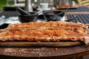 Marinated BBQ pork ribs on a wooden backyard table. Preparation process of barbeque for Grilling, Smoking, Baking and Roasting. Lifestyle concept.