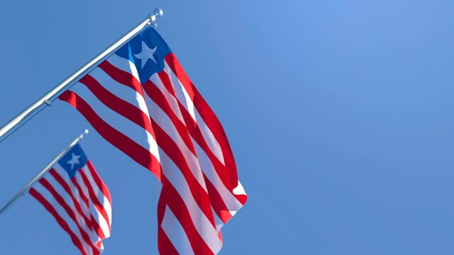 The national flag of Liberia is flying in the wind against a blue sky