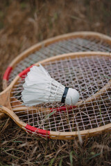 Wooden badminton rackets and a white feather shuttlecock. The game of badminton.