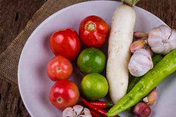Fresh vegetables on a plate placed on a wooden table.