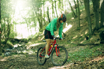 Fototapeta premium Mountain Bike cyclist woman riding bike in forest. Outdoor cyclist woman enjoying at nature.