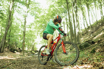 Fototapeta na wymiar Mountain Bike cyclist woman riding bike in forest. Outdoor cyclist woman enjoying at nature.