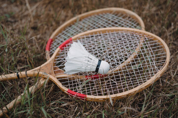 Wooden badminton rackets and a white feather shuttlecock. The game of badminton.